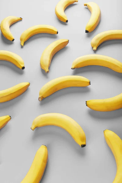 Bright pattern of yellow bananas on a gray background. View from above. Flat lay. Fruit patterns