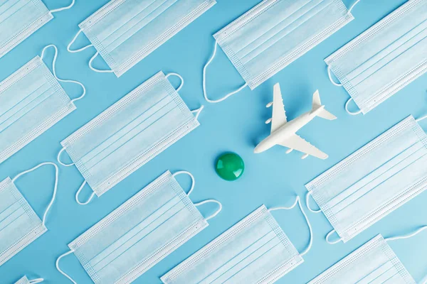 The plane is surrounded by medical masks on a blue background with a green dot of the destination. The concept of opening borders and freedom of movement in the territory. The impact of viruses on the airline