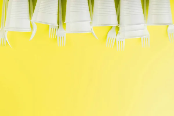 Plastic tableware on a yellow background with free space. Disposable tableware