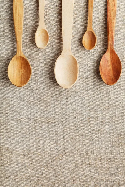 Natural wood spoons in a row on burlap fabric. Natural natural materials. Caring for the environment