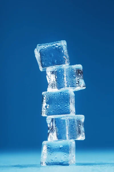 Cubes of melting ice tower on a blue background. Free space