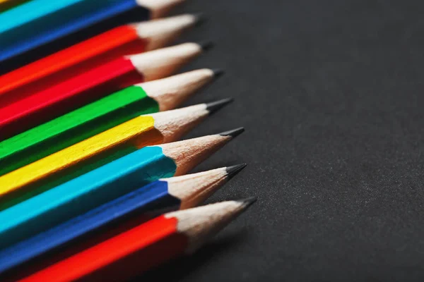 A set of colorful pencils on a textured dark background.