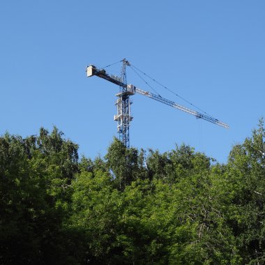 Vinç yeşil ağaçların üzerinden bina