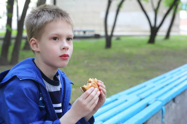 Pojken äta hamburgare — Stockfoto