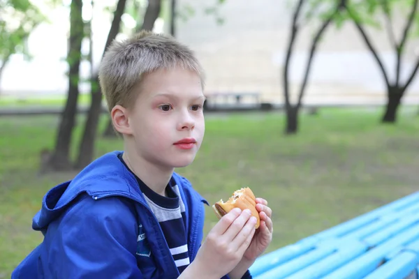 Pojken äta hamburgare — Stockfoto