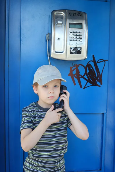 Мальчик разговаривает по уличному телефону — стоковое фото
