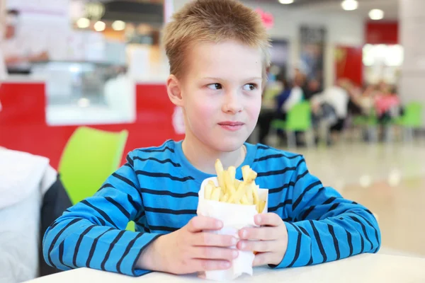 Garçon avec les pommes de terre frites — Photo