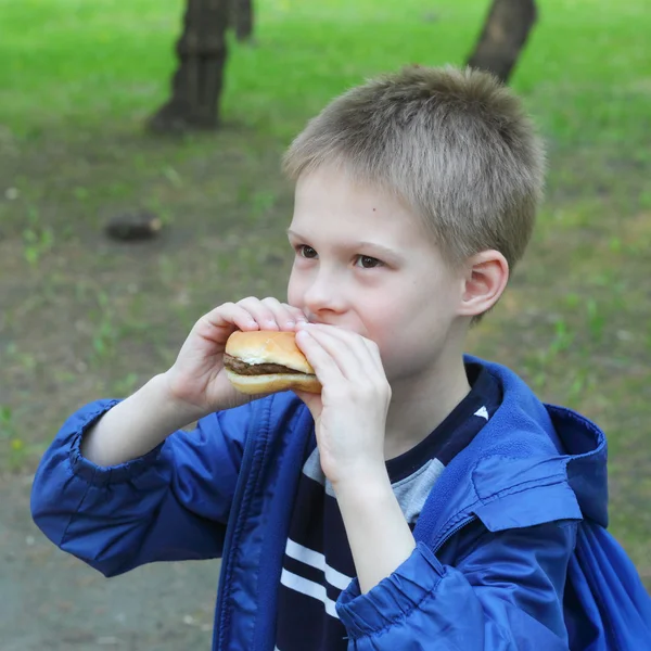 Malý chlapec jíst hamburger — Stock fotografie