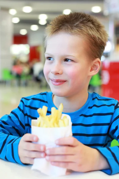 Liten pojke med french-fried potatis — Stockfoto