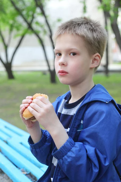 Lilla pojken äta hamburgare — Stockfoto