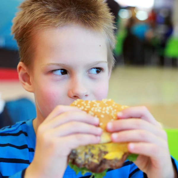 Lilla pojken äta burger — Stockfoto