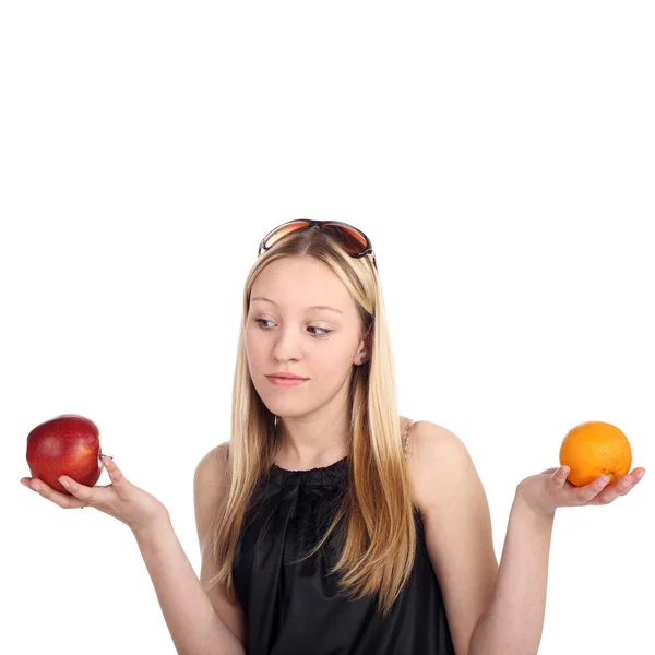 Дівчина вибирає між яблуком і апельсином — стокове фото