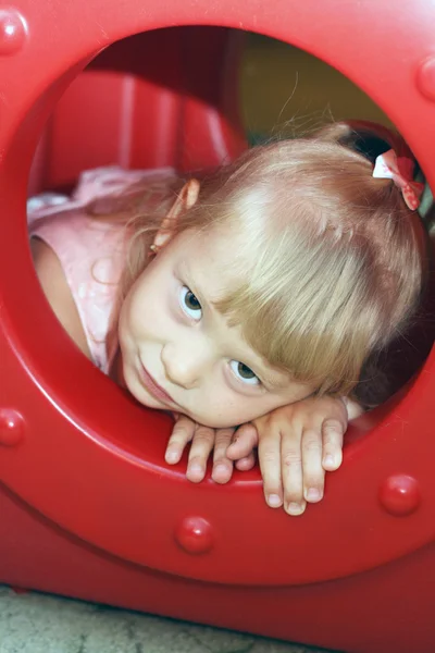 Meisje op zoek uit speelgoed raam — Stockfoto