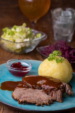 Alman sauerbraten ve tahtanın üzerinde patates köftesi.