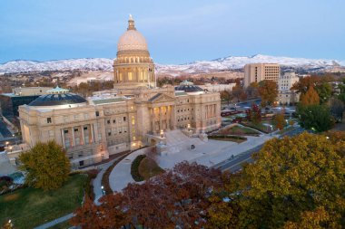 İHA 'dan görüldüğü gibi Boise sermayesi. Bina, alacakaranlıkta arkasında dağlar olan ağaçlarla çevrili.