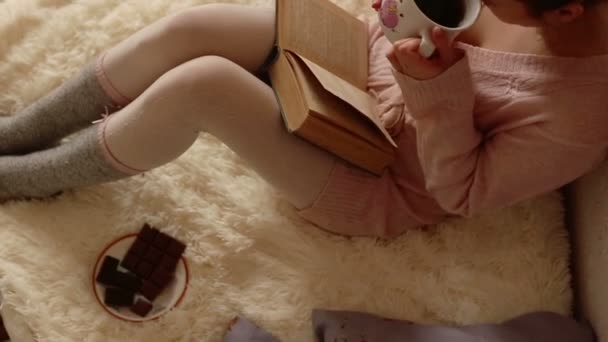 Junge Frau liest ein Buch und trinkt Kaffee — Stockvideo