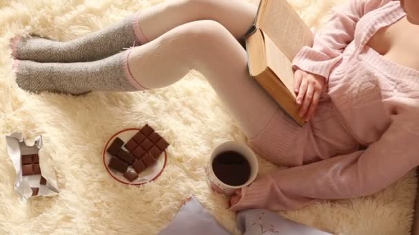 Ung kvinna läser en bok och dricker kaffe — Stockvideo