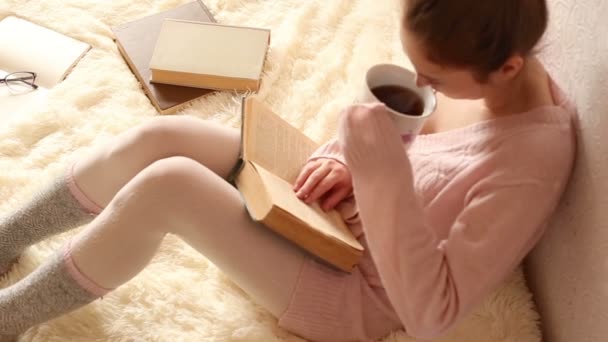 Junge Frau liest ein Buch und trinkt Kaffee — Stockvideo