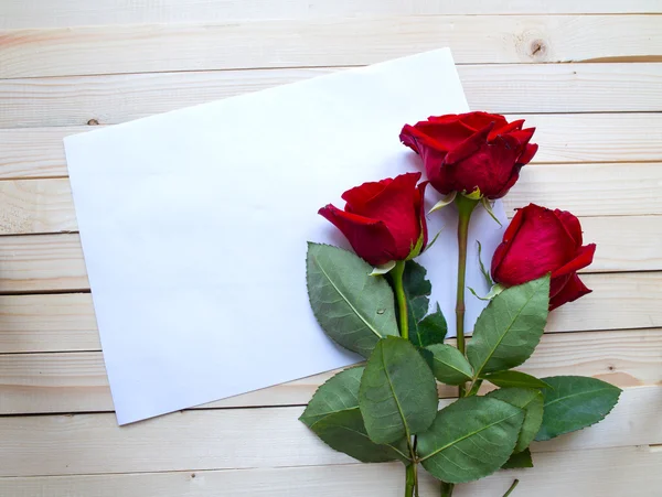 Rosas vermelhas em uma mesa de madeira — Fotografia de Stock