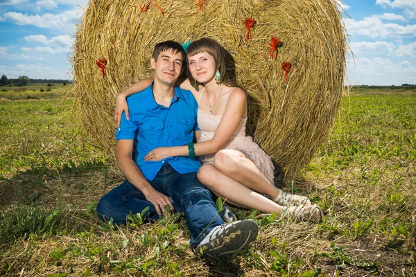 Young couple sitting near haystack — Stock Photo, Image