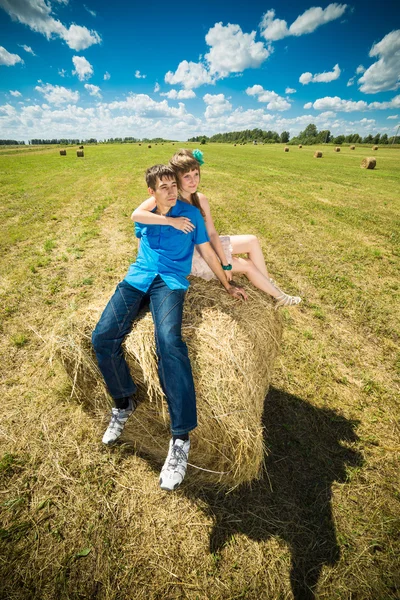 Young couple sitting on a hay stack — Stock Photo, Image