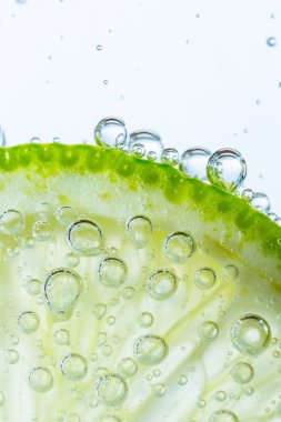 Slice of lime in water with bubbles
