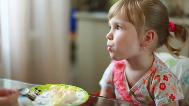 Liten flicka äter vid bordet — Stockvideo