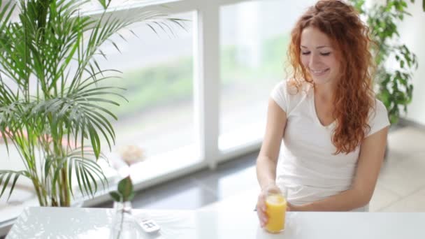 Mujer sentada a la mesa bebiendo jugo — Vídeos de Stock