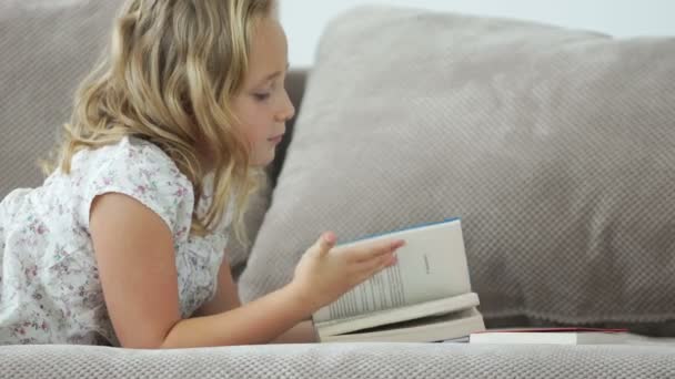 Niña en el libro de lectura sofá — Vídeo de stock