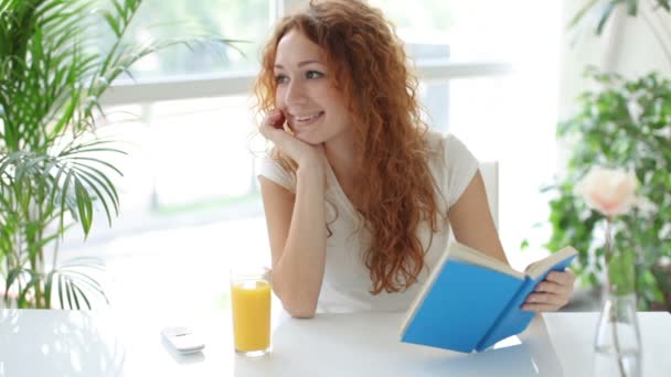 Mujer sentada en la mesa y leyendo libro . — Vídeos de Stock