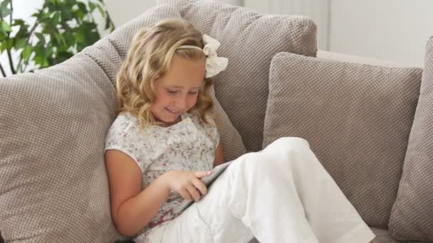Κορίτσι στον καναπέ παίζοντας σε tablet pc — Αρχείο Βίντεο