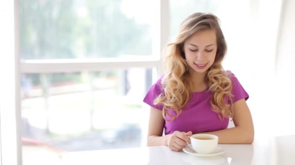 Vrouw zitten aan tafel drinken koffie — Stockvideo