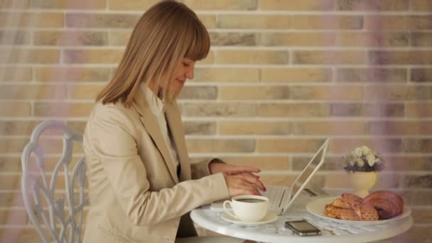 Woman sitting at cafe using laptop — Stock Video