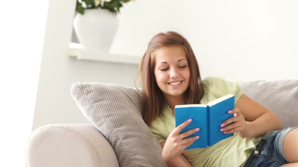 Mujer sentada en un sofá con libro — Vídeo de stock