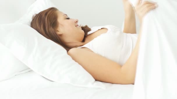 Молодая женщина, лежащая в постели — стоковое видео