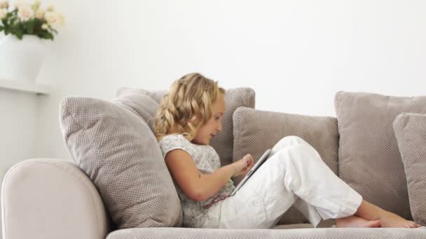 Niña en el sofá con la tableta PC — Vídeos de Stock