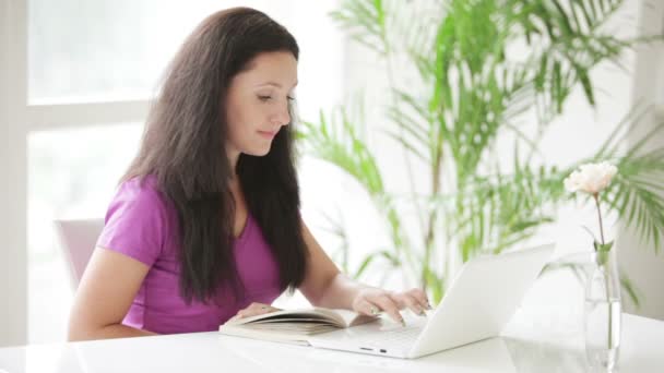 Mujer sentada a la mesa leyendo libro — Vídeos de Stock