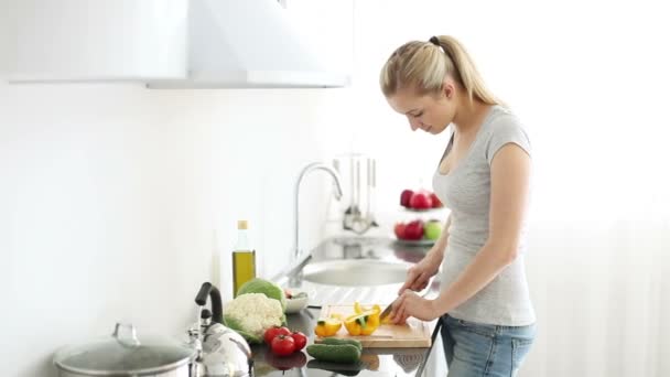 Vrouw in keuken snijden paprika — Stockvideo