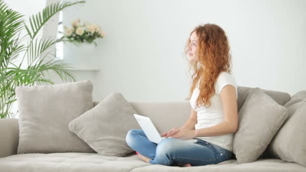 Femme assise sur le canapé en utilisant un ordinateur portable — Video