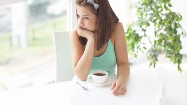 Girl sitting at table drinking coffee — Stock Video