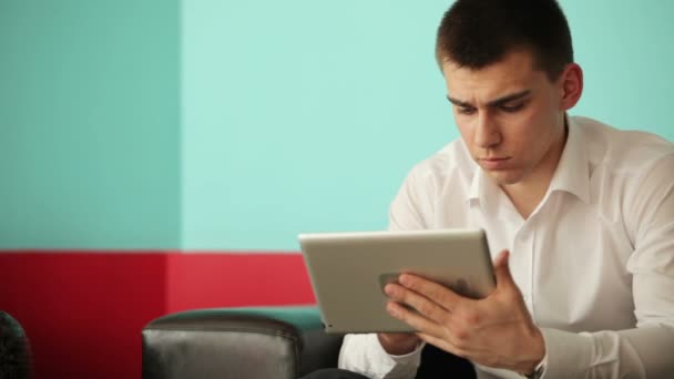 Молодий чоловік друкує на планшеті — стокове відео