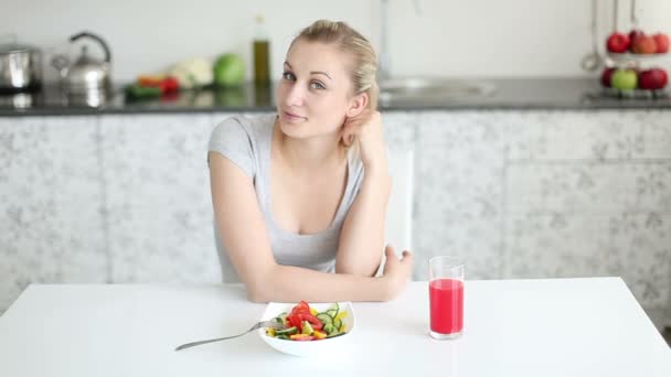 Mooie jonge vrouw die aan de keukentafel zit — Stockvideo