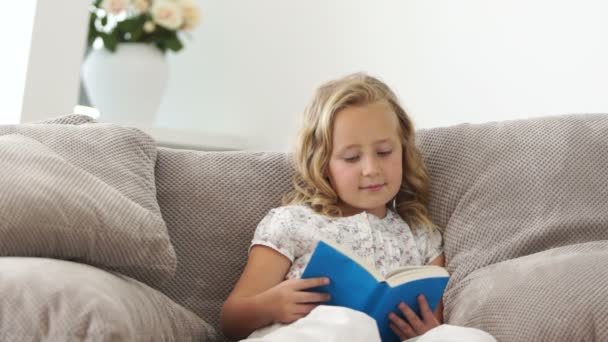 Mädchen liest ein Buch auf dem Sofa — Stockvideo