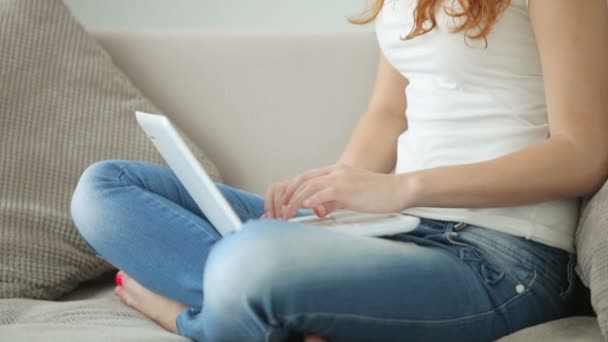 Chica sentada en el sofá utilizando el ordenador portátil — Vídeos de Stock