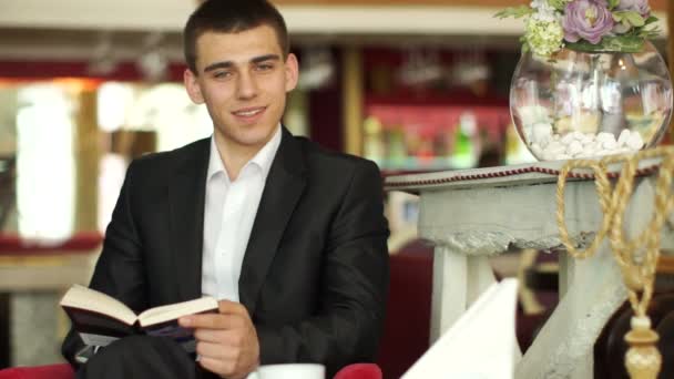 Un type assis dans un café et lisant — Video