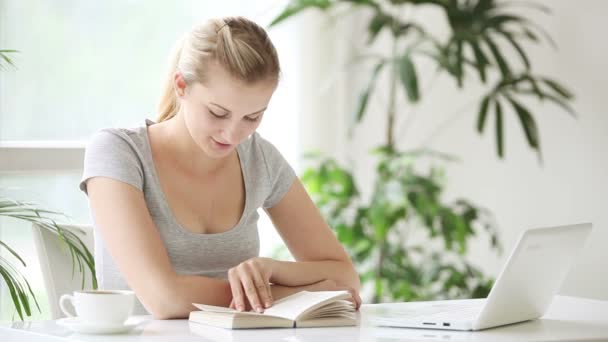 Mujer sentada a la mesa leyendo — Vídeos de Stock