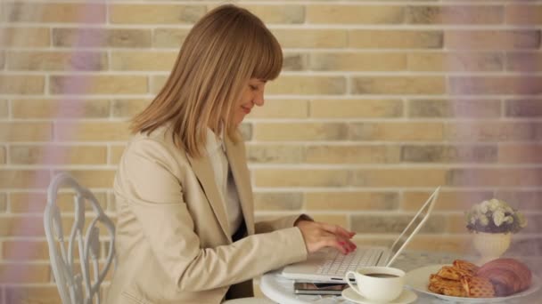 Женщина сидит в кафе с ноутбуком — стоковое видео