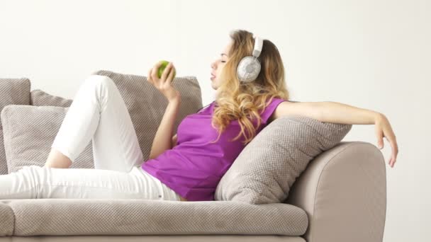Женщина лежит на диване и ест яблоко — стоковое видео