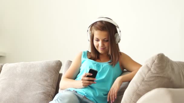 Kobieta w słuchawki rozciągający się na kanapie — Wideo stockowe