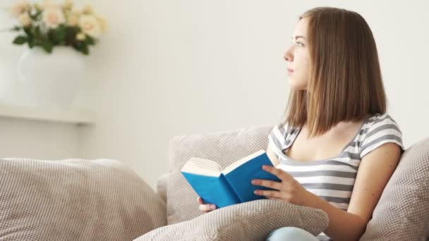 女孩坐在沙发上，阅读 — 图库视频影像